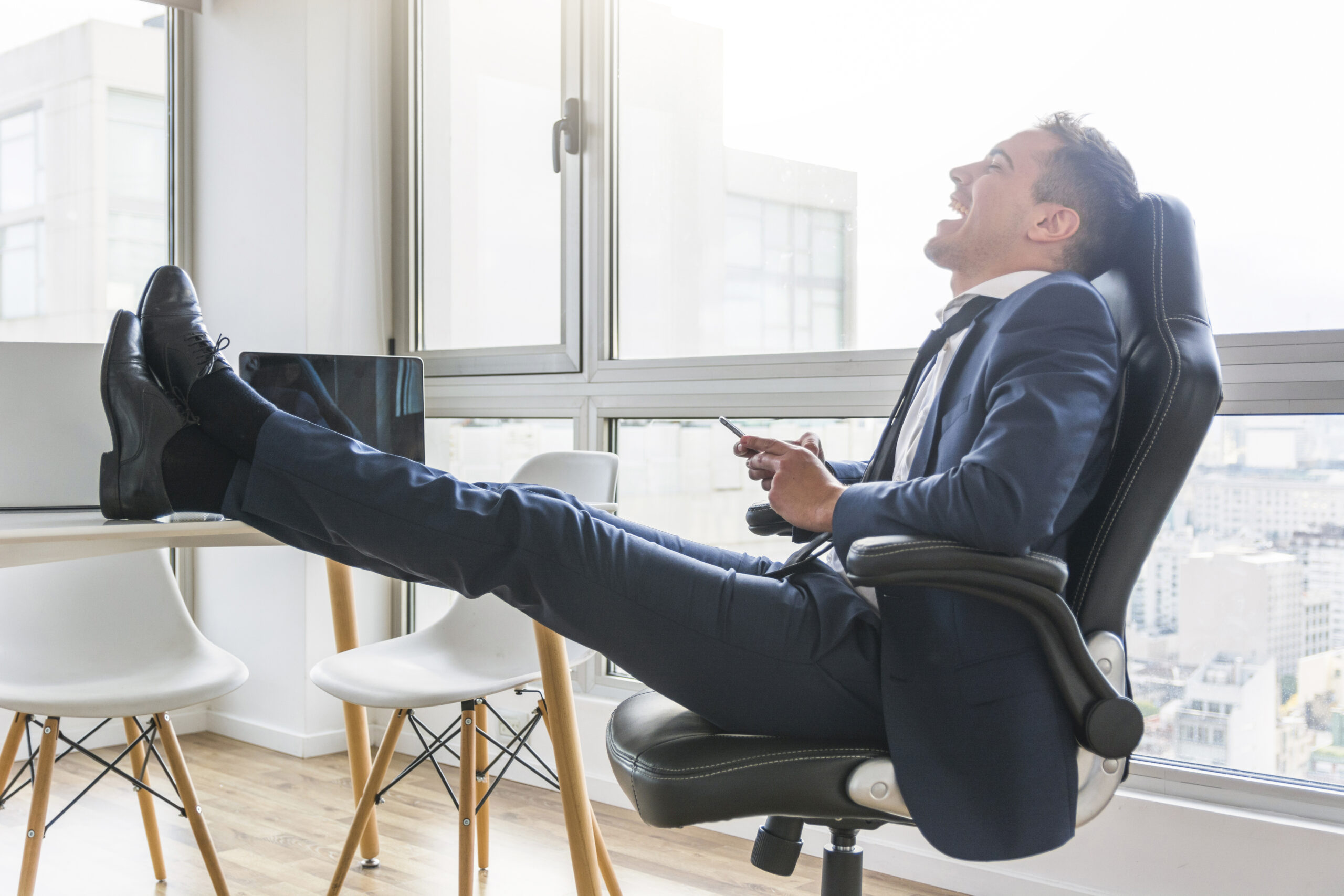 A happy businessman smiling while sitting on leather chair