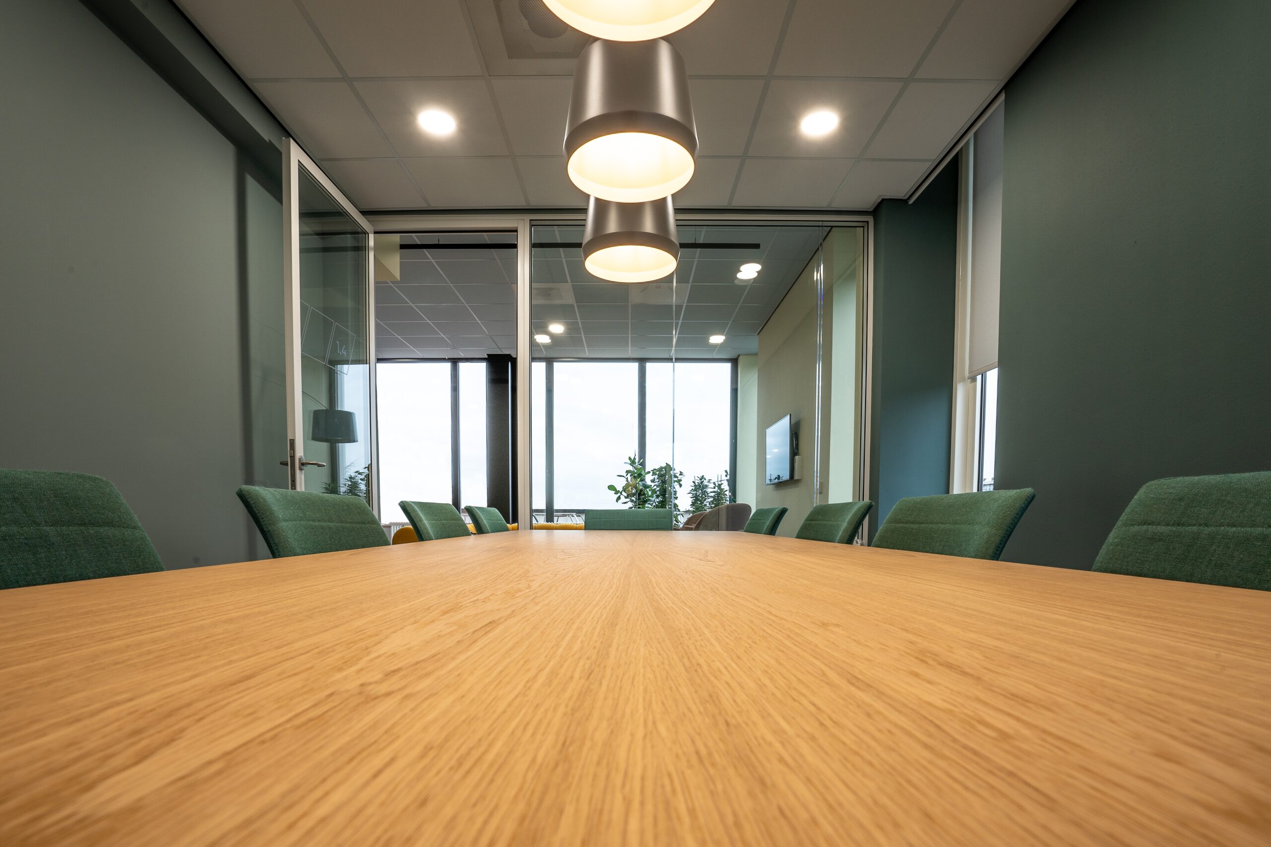 Brown wooden office meeting desk with green chairs
