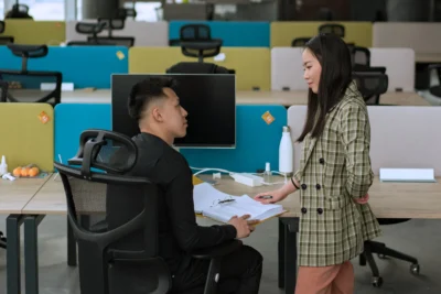 Ergo Chair at Work: What Singapore Employers Should Actually Look For 2 Coworkers discussing beside an Ergo Chair.